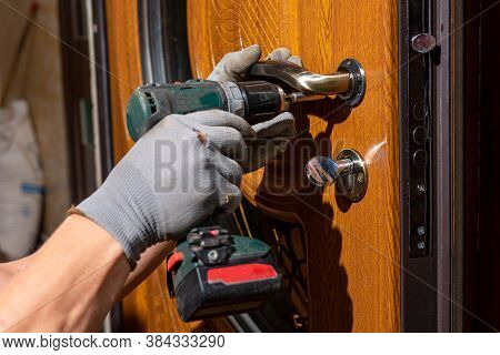The Master Worker Installs A Door Lock In The Front Door, Metal Doors With A Polymer Coating.