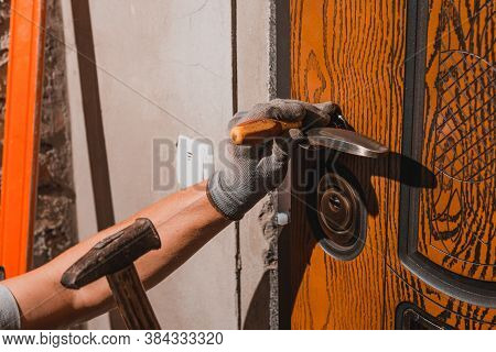 The Young Master Skillfully And Professionally Installs A Lock In The Front Door Of A Private House,