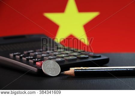 Two Hundred Vietnam Dong Coin On Reverse (vnd) With Black Calculator And Two Pencils On Black Floor 