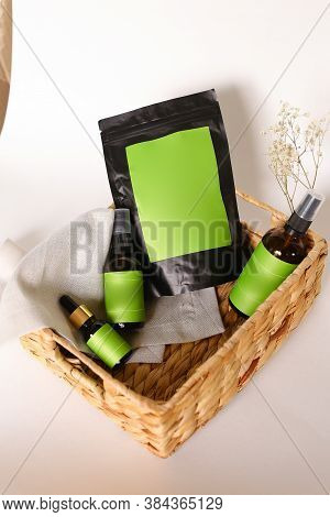 Black Doy Pack And Spray Bottles With Cosmetic Products In Wicker Basket, Green Space For Your Brand