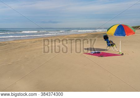 Image Of Bright Beach Umbrella, Beach Chair And Bedding On Deserted Bufalara Beach In Italian Provin