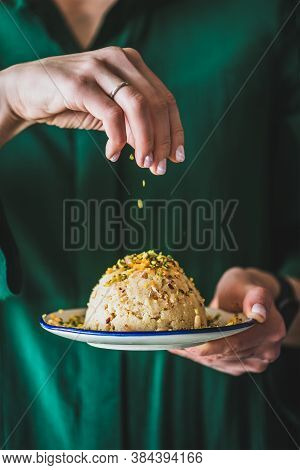 Womans Hand Puring Pistachio Nuts To Sweet Semolina Helva