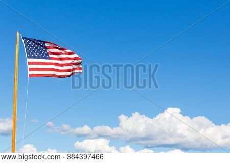 Stars and stripes American flag fluttering in the wind, Bar Harbor, Maine, USA. Summer blue sky and cloud background with space for text.