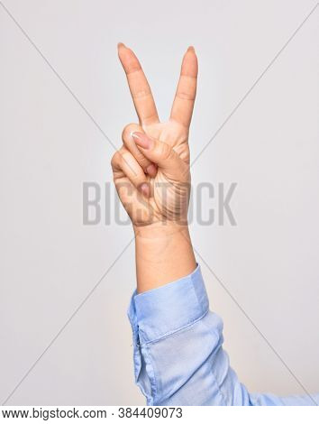 Hand of caucasian young woman doing victory symbol showing number two with streched fingers raised up over isolated white background