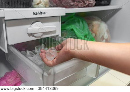 The Girl Takes Ice From The Ice Maker Of The Freezer For Cooling Drinks.