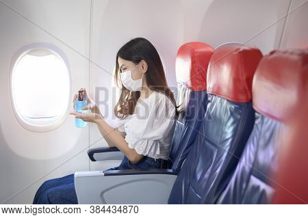 A Travelling Woman Is Wearing Protective Mask Is Washing Hands With Alcohol Gel Onboard In The Aircr