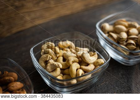 Almond, Cachew And Walnut In A Small Plates Which Standing On A Black Table. Nuts Is A Healthy Veget