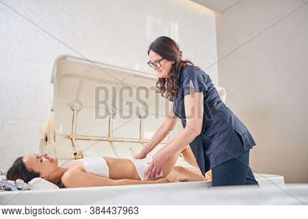 Friendly Cosmetologist Smiling To The Young Lady In Her Clinic