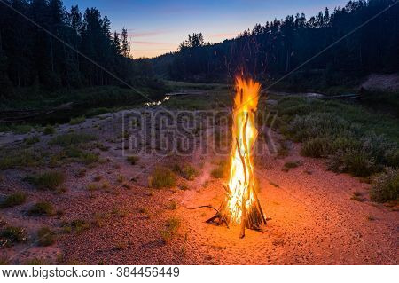 Landscape Of Forest And River. Sunset Sky. Huge Fire. Midsummer Ligo Celebration. Latvian Tradition.