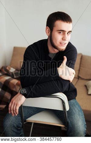 Handsome Man Wearing A Black Jacket And Jeans Sitting Down Intside