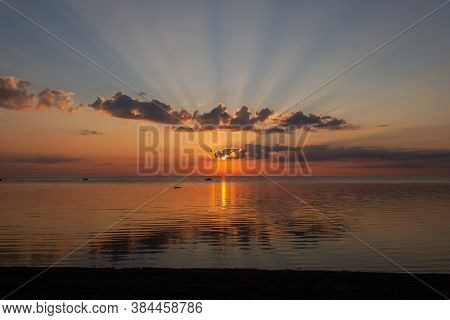 Sun With Rays In Sky Behind Clouds During Sunrise Over Sea