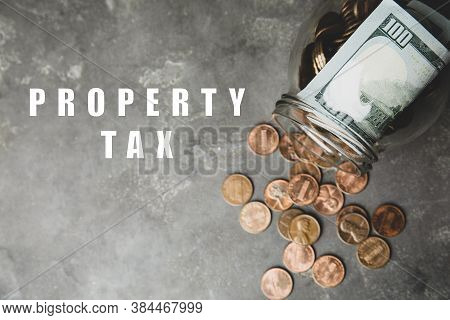 Text Property Tax Near Jar With Dollars And Coins On Grey Table, Top View