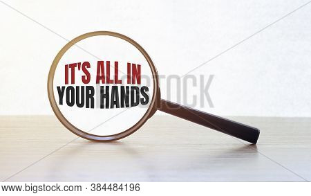 Magnifying Glass With Text Its All In Your Hands On Wooden Table.