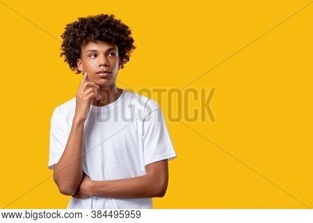 Pensive Black Teenager. Make Decision. Confused Yong African Guy Isolated On Orange Copy Space. Crea