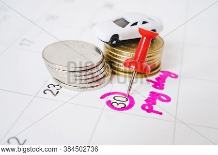 Green Thumbtack Marked On End Of Month On White Calendar And Blurred White Car And Stack Of Coins  W