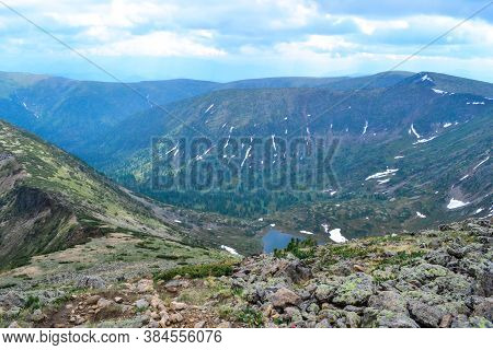 Rocks On Mountain Ridge, View Of Mountain Lake In Form Of Heart Among Snow Ice Glaciers, Green Mount