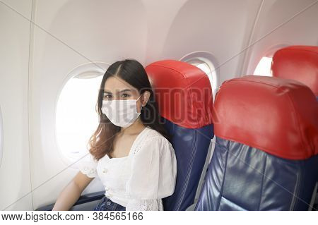 A Travelling Woman Is Wearing Protective Mask Onboard In The Aircraft, Travel Under Covid-19 Pandemi