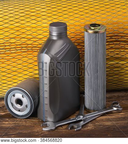 A Set Of Car Supplies Items, On A Yellow Background And A Wooden Table, An Oil Air Filter And Spanne