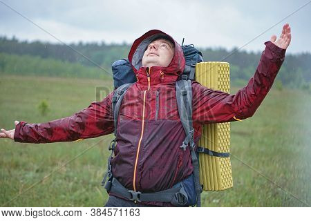 Guy Hiker With A Tourist Backpack Smiles In The Rain In The Mountains