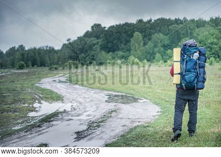 Guy Tourist Hiker Walks Along The Road With A Backpack In A Red Jacket In The Rain