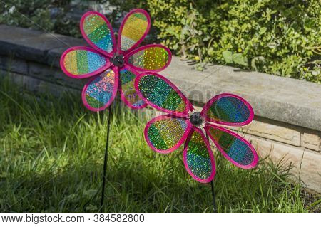 Two Pinwheels Made Of Multicoloured Plastic Curls Attached At Their Axles To Sticks By Pins, Designe