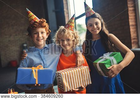 Three Friends In Bday Hats Holding Presents