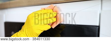 Close-up Of Persons Hand In Yellow Protective Gloves Cleaning Kitchen Appliance With Pink Rag. Moder