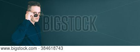 Banner. Business Man, In The Studio, Looks Through, Glasses. On A Black Background.