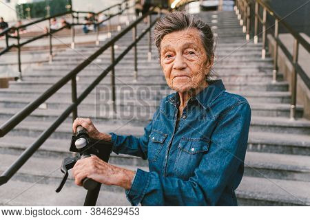 Cheerful Elderly Woman On A Scooter. Grandma Rides A Scooter. Grandmother Using Urban Personal Trans