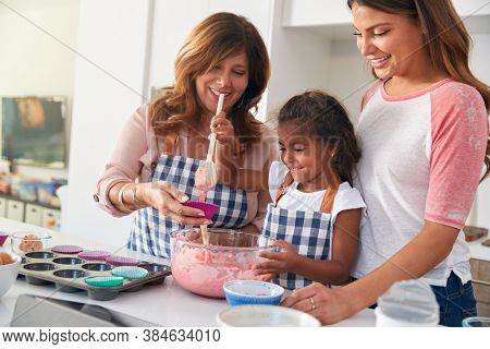 Multi-Generation Hispanic Female Family Having Fun In Kitchen At Making Cake Together