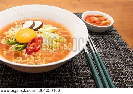 Korean Spicy Instant Noodle, Ramyun, With Egg Yolk, Kimchi, And Eating Utensils