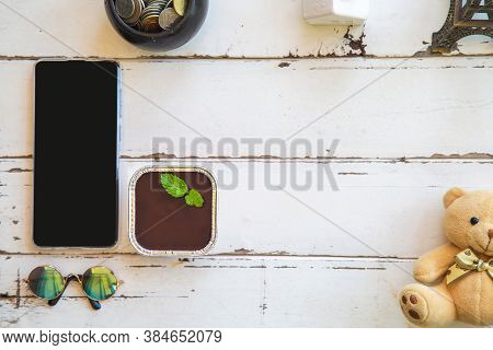 Top View Chocolate Fudge Cake With Peppermint On A White Wooden Table With A Mobile Phone And Decora