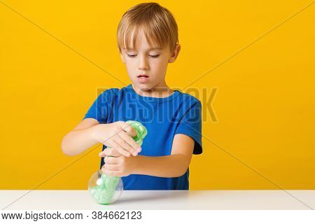 Cute Boy Playing With Popular Slime. Kid Having Fun With Slime Toy. Creative Child Takes Green Slime