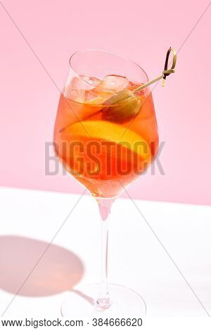 Aperol spritz on pink background. Pink and white background. Hard light and shadow