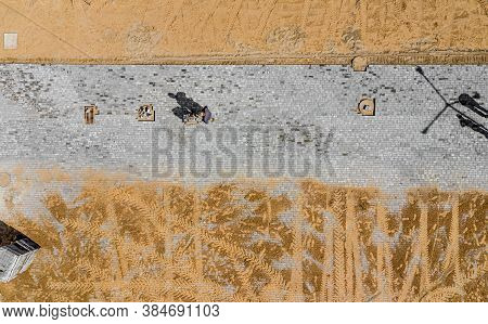 Worker With Vibratory Plate Compactor Compacting Sand At Road Or Sidewalk Construction Site Top View