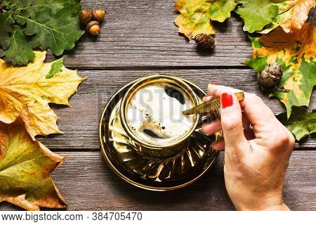 Composition With Female Hand Holding Cup Of Pumpkin Latte With Marshmallow,  Leaves And Pumpkin On W