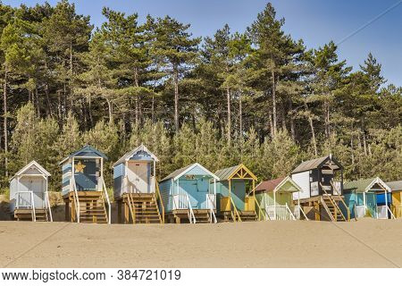 29 June 2019: Wells-next-the-sea, Norfolk, England, Uk - Bathing Huts On The Beach, Pine Trees Behin
