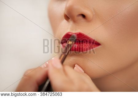 Unrecognizable Makeup Artist Using Red Lipstick On The Lips Of A Woman