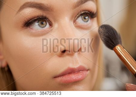 Cropped Close Up Of A Professional Makeup Artist Applying Highlighter On The Face Of Beautiful Woman