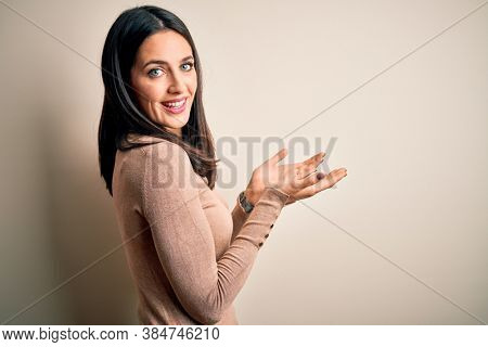 Young brunette woman with blue eyes wearing casual sweater over isolated white background pointing aside with hands open palms showing copy space, presenting advertisement smiling excited happy