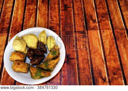 Oriental, Turkish, Azerbaijani Baklava Sweets In A White Plate On A Brown Wooden Table, Copy Space.