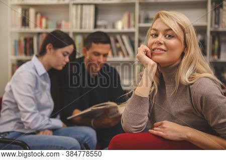 Gorgeous Happy Blond Haired Woman Smiling To The Camera, Relaxing At College Library With Her Friend