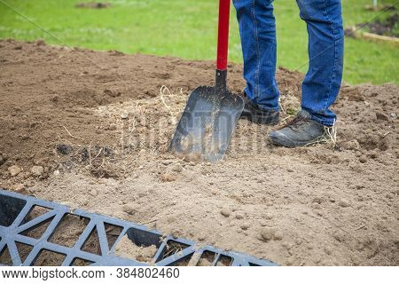The Gardener Sprinkles A Flower Bed With A Shovel. Creation Of Landscape Design In The Garden. The M