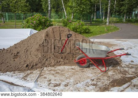 The Gardener Sprinkles A Flower Bed With A Shovel. Creation Of Landscape Design In The Garden. The M
