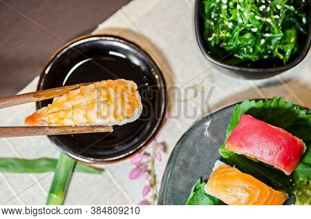 Hand Holding Wooden Chopsticks Tongs Sushi At Japanese Food Restaurant.