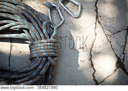 Coiled Climbing Rope And Steel Carabiner. Mountain Climbing Equipment: Harness, Brakes, Quickdraws, 