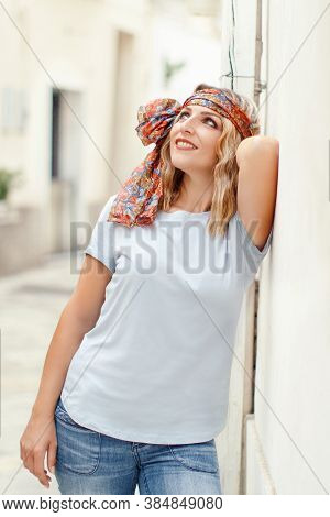 Young Women Wearing T-shirt And Jeans Stays Near A Wall
