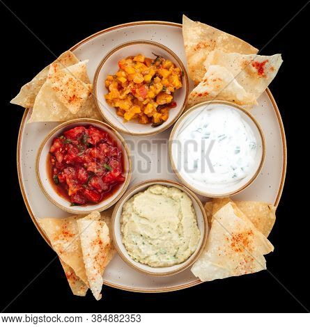 Top View On A Plate With Different Sauce Toppings And Chips Isolated On Black