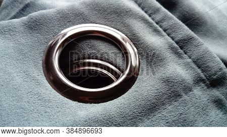 Close-up Of A Metal Eyelet On A Gray-blue Curtain Made Of Thick Velvety Fabric