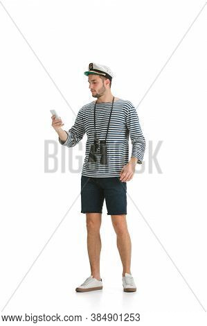 Scrolling Phone. Caucasian Male Sailor In Uniform On White Studio Background. Young Man Using Modern